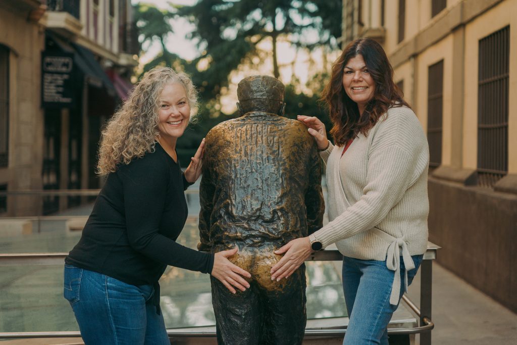 two women posing with statue