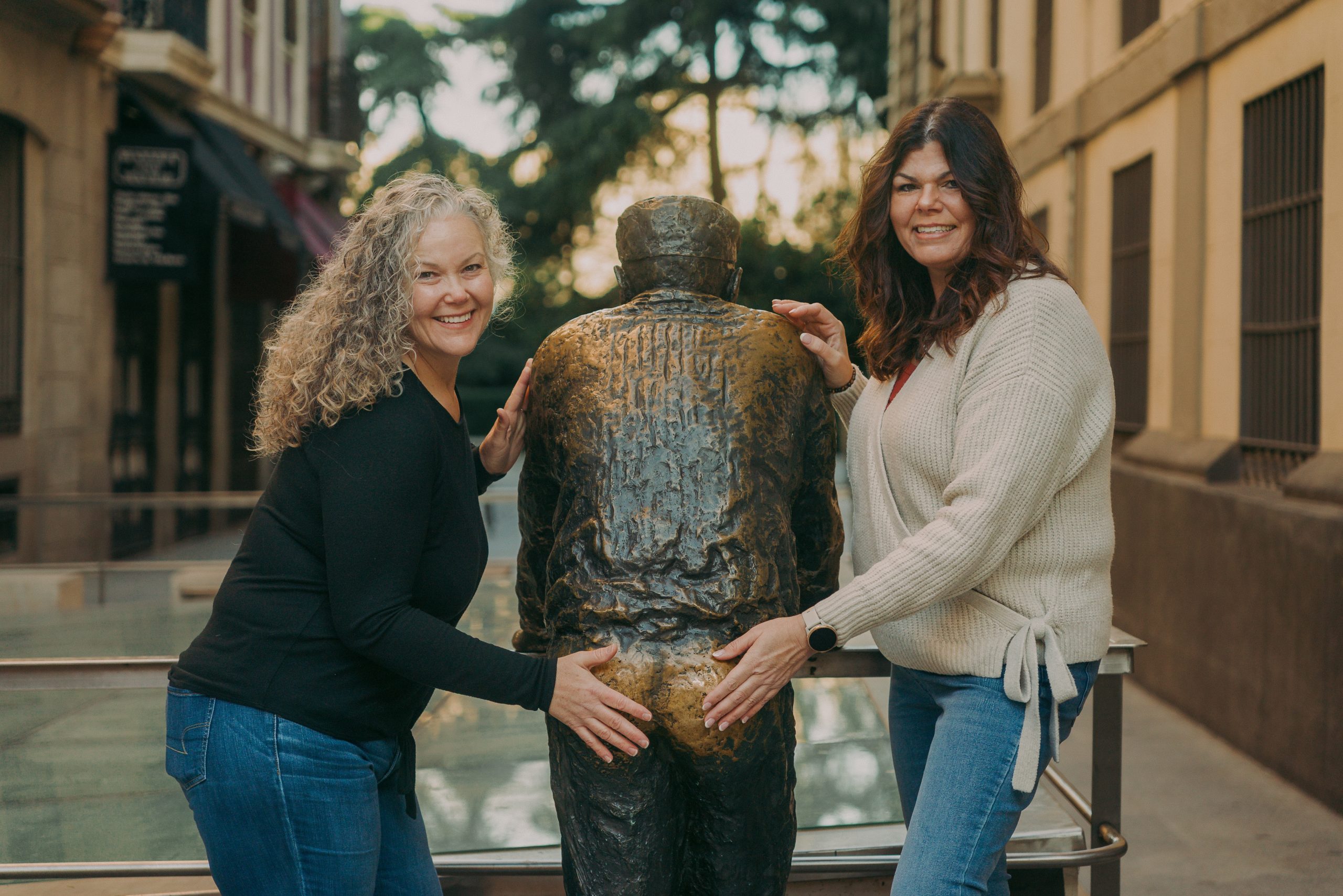 two women posing with statue