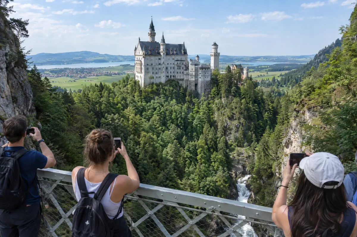 Visitors photographing Neuschwanstein Castle from Mary's Bridge above the Pöllat Gorge